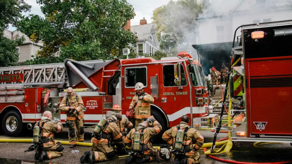 Firefighters next to their trucks after putting out a house fire