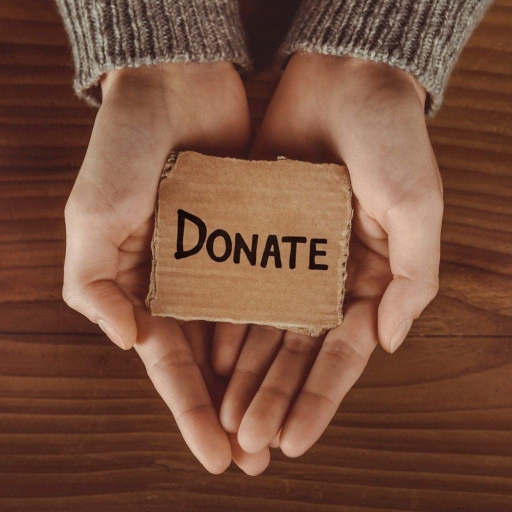 Hands holding sign that says DONATE