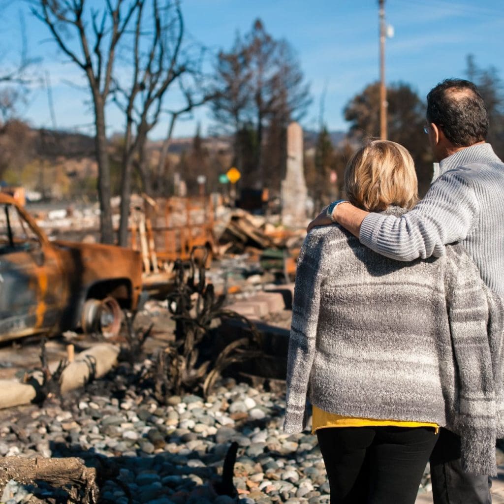 People looking at fire damaged car and property